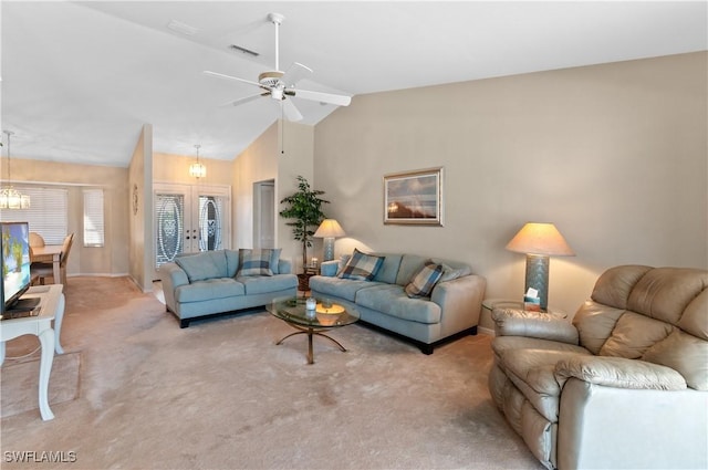 living room with ceiling fan with notable chandelier, vaulted ceiling, light colored carpet, and french doors