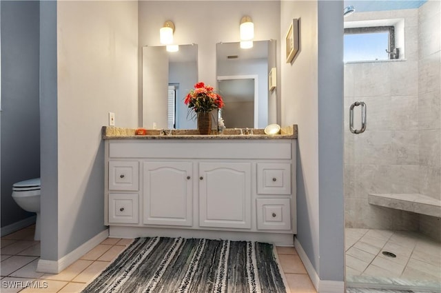 bathroom featuring walk in shower, vanity, toilet, and tile patterned flooring