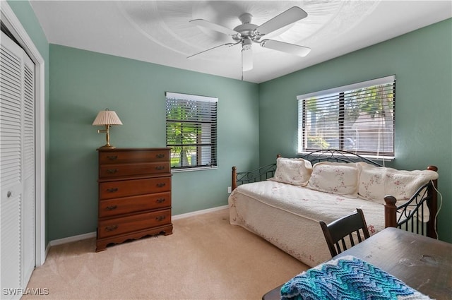 bedroom with ceiling fan, multiple windows, light colored carpet, and a closet