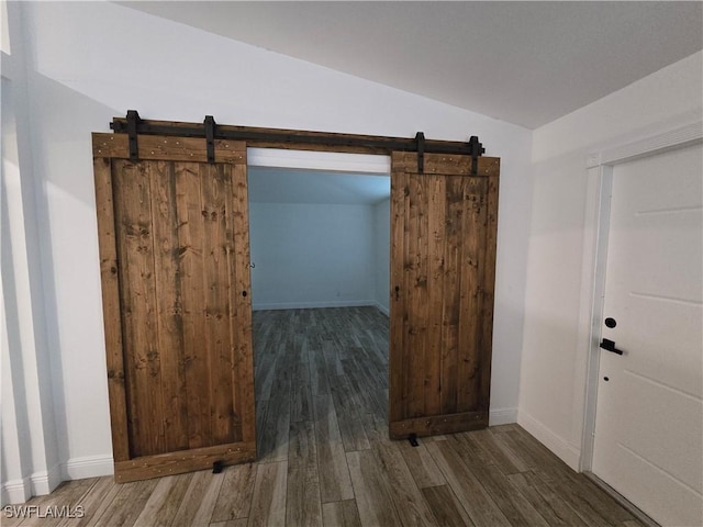 interior space featuring a barn door, lofted ceiling, and dark hardwood / wood-style flooring