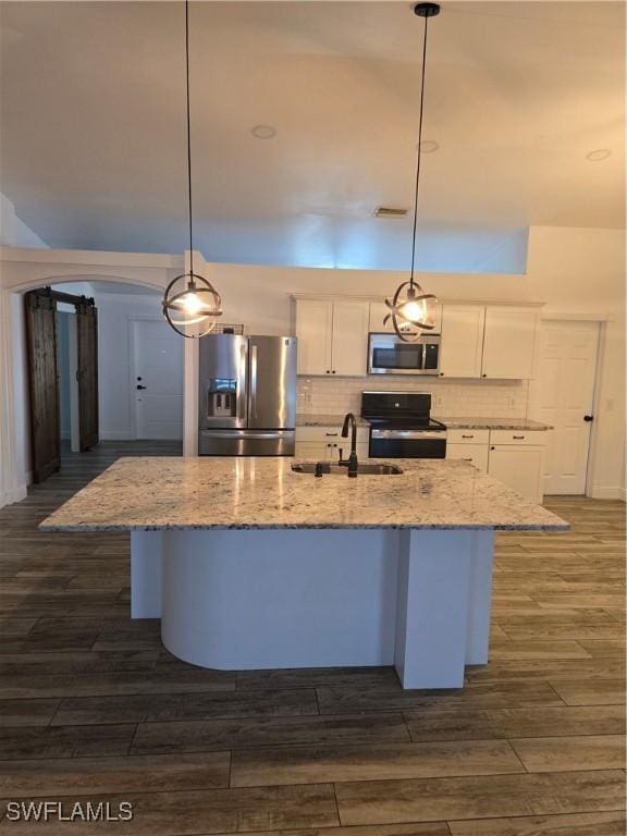 kitchen with a kitchen island with sink, decorative light fixtures, stainless steel appliances, and white cabinetry