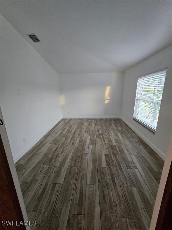 unfurnished room featuring lofted ceiling and dark hardwood / wood-style floors