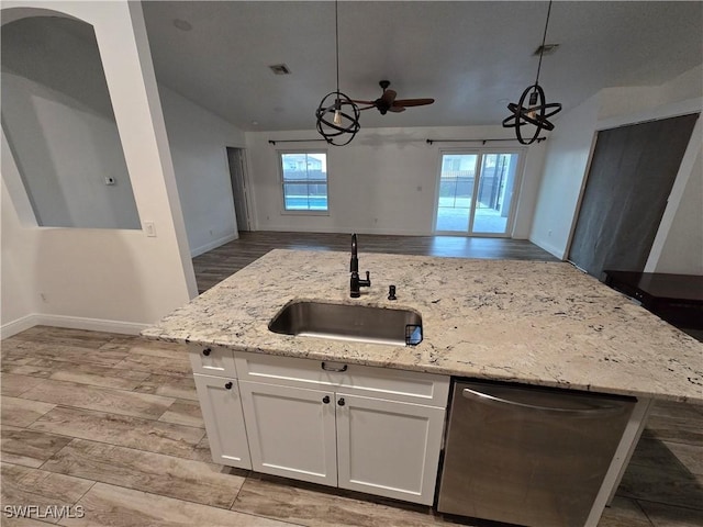 kitchen featuring sink, white cabinetry, light stone counters, light hardwood / wood-style floors, and decorative light fixtures