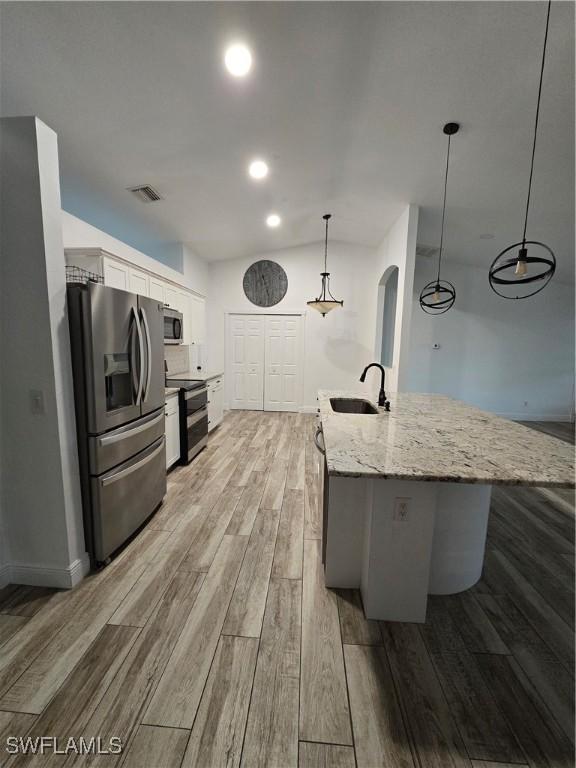 kitchen featuring pendant lighting, sink, a kitchen island with sink, stainless steel appliances, and white cabinets