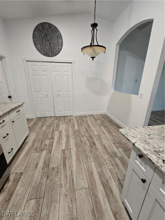 unfurnished dining area featuring lofted ceiling and light hardwood / wood-style flooring