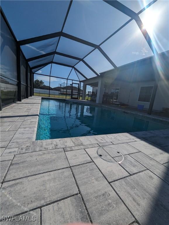 view of swimming pool featuring a patio and glass enclosure