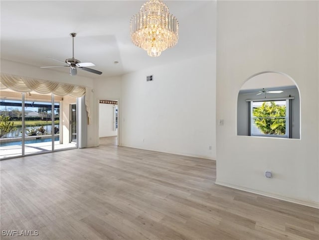 unfurnished living room featuring ceiling fan with notable chandelier and light hardwood / wood-style floors