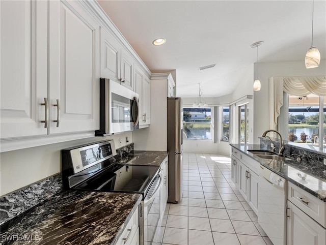 kitchen featuring sink, white cabinetry, stainless steel appliances, decorative light fixtures, and dark stone counters