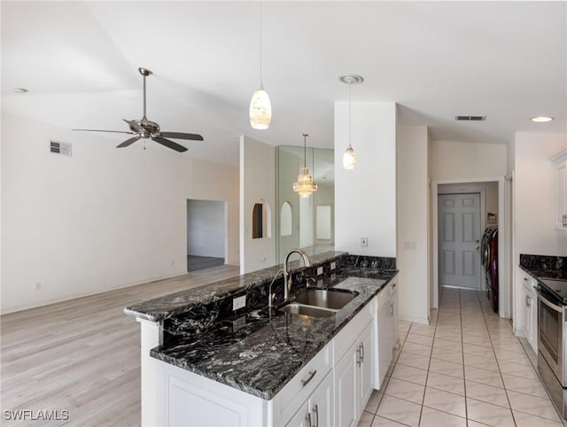 kitchen with dark stone countertops, decorative light fixtures, sink, and white cabinets