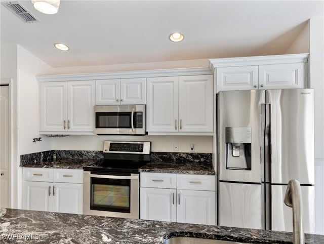 kitchen featuring white cabinetry, appliances with stainless steel finishes, and dark stone counters