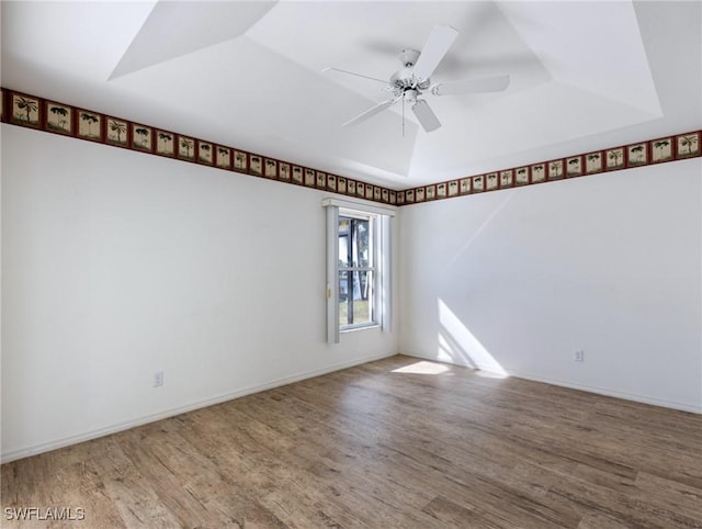 spare room with ceiling fan, a tray ceiling, and hardwood / wood-style floors