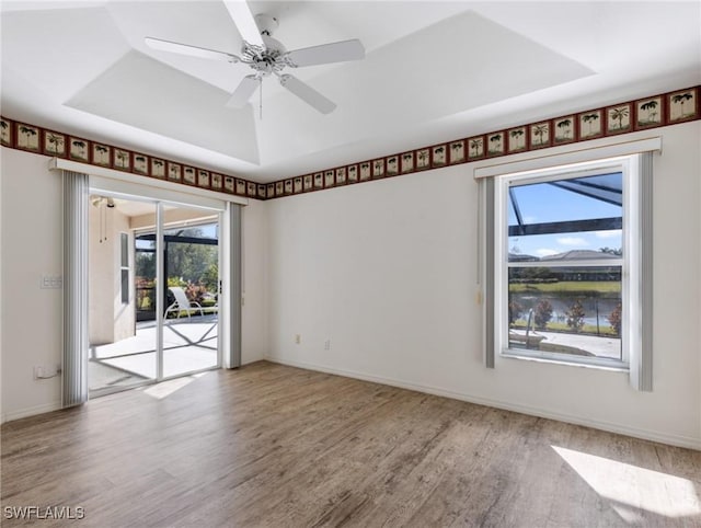 unfurnished room with ceiling fan, wood-type flooring, and a tray ceiling