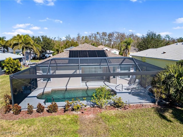 rear view of house with a lanai, a patio area, solar panels, and a lawn