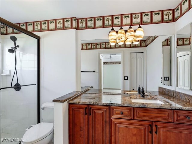 bathroom with vanity, a shower with door, and toilet