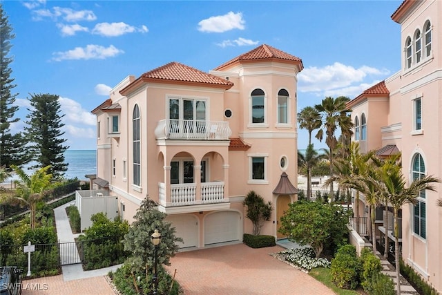 mediterranean / spanish-style home featuring a water view, a balcony, and a garage