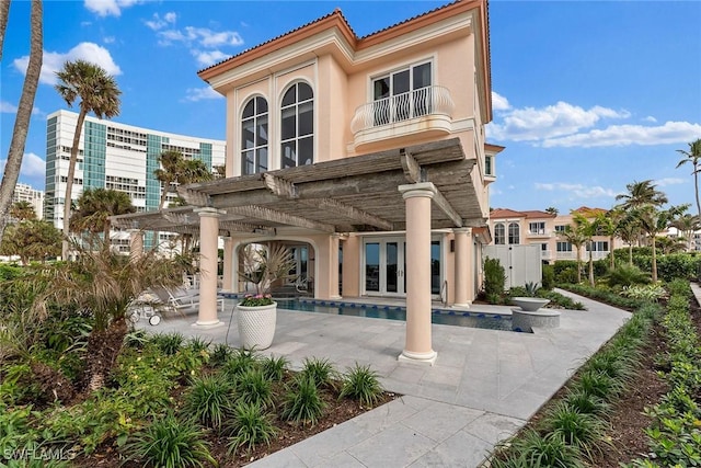 rear view of property featuring a pergola, a patio, a balcony, and french doors