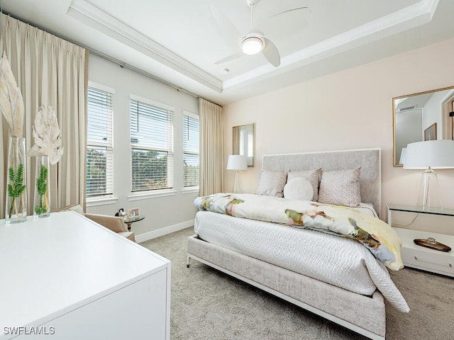 carpeted bedroom with ornamental molding, ceiling fan, and a tray ceiling