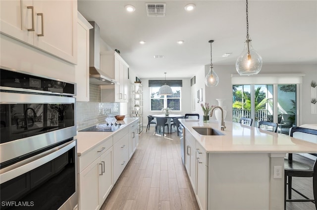 kitchen featuring stainless steel appliances, sink, an island with sink, and white cabinets