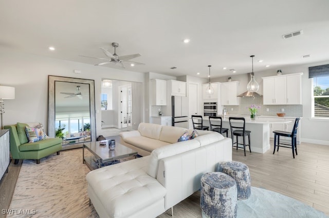 living room with ceiling fan and light wood-type flooring