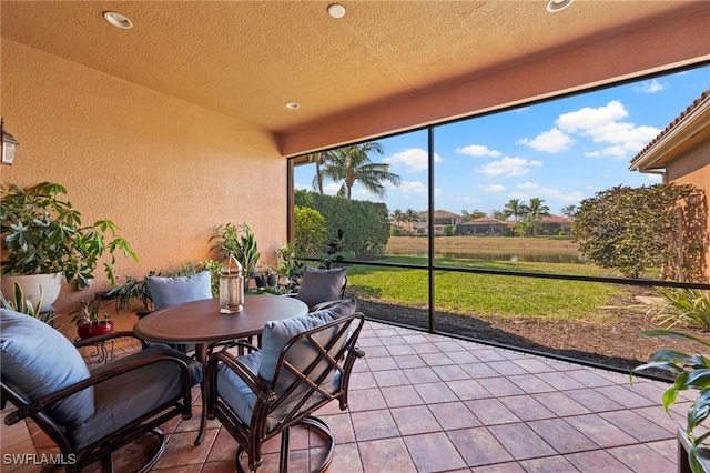 sunroom featuring a water view