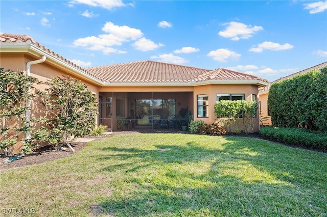 rear view of property featuring a sunroom and a lawn