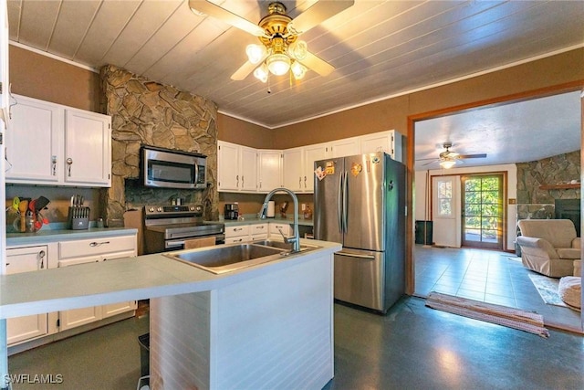 kitchen featuring appliances with stainless steel finishes, white cabinetry, a kitchen island with sink, a stone fireplace, and wooden ceiling