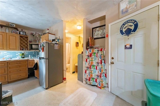 kitchen featuring tasteful backsplash, stainless steel fridge, and sink