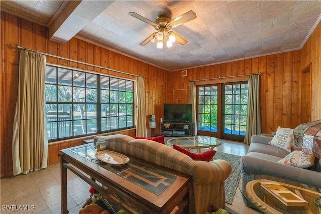 living room with a healthy amount of sunlight, light tile patterned floors, ceiling fan, and wood walls