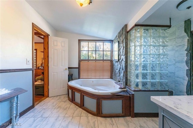 bathroom featuring vanity, a bathtub, and vaulted ceiling