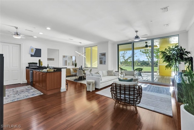 living room featuring dark wood-type flooring, ceiling fan, sink, and a wall of windows