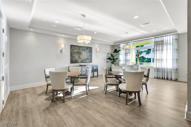 dining room with a tray ceiling and light wood-type flooring