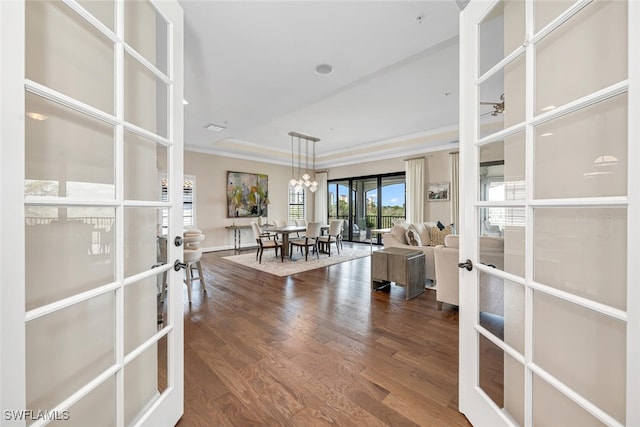 interior space with hardwood / wood-style flooring, a tray ceiling, ornamental molding, french doors, and a chandelier