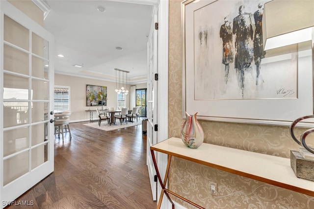 corridor featuring wood-type flooring, ornamental molding, a healthy amount of sunlight, and french doors