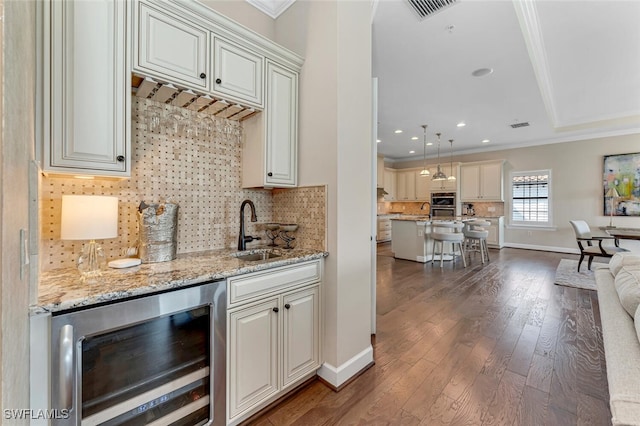 kitchen featuring sink, hanging light fixtures, ornamental molding, dark hardwood / wood-style flooring, and beverage cooler