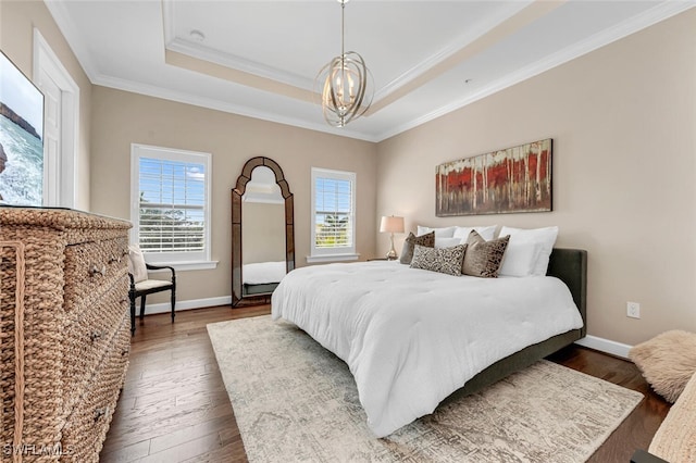 bedroom with a notable chandelier, a tray ceiling, ornamental molding, and dark hardwood / wood-style floors