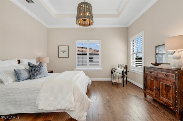 bedroom featuring wood-type flooring, ornamental molding, and a tray ceiling