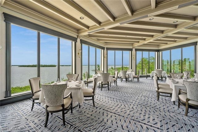 sunroom featuring a water view, plenty of natural light, and beamed ceiling