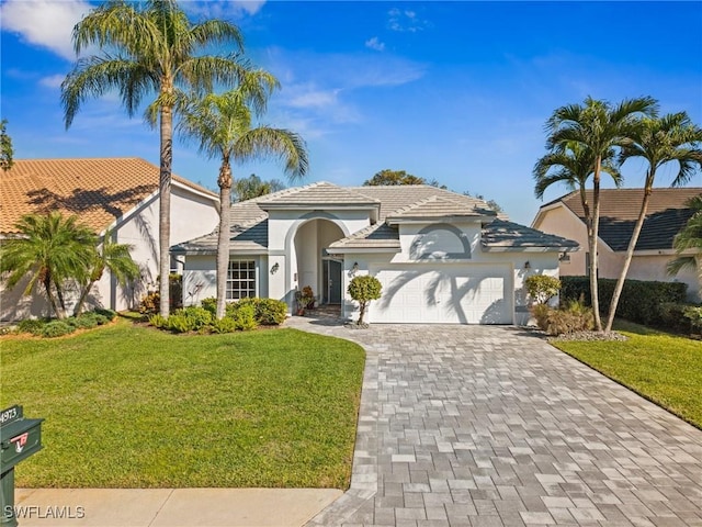 24973 Bay Cedar Dr, Bonita Springs, FL 34134 - mediterranean / spanish-style house featuring stucco siding, decorative driveway, an attached garage, a front yard, and a tiled roof