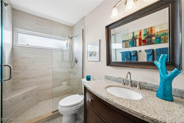 full bathroom with toilet, tiled shower, and vanity