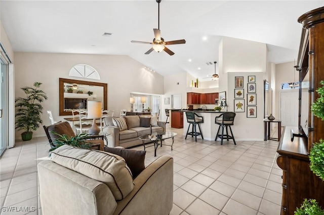 living room featuring baseboards, vaulted ceiling, a ceiling fan, and light tile patterned flooring