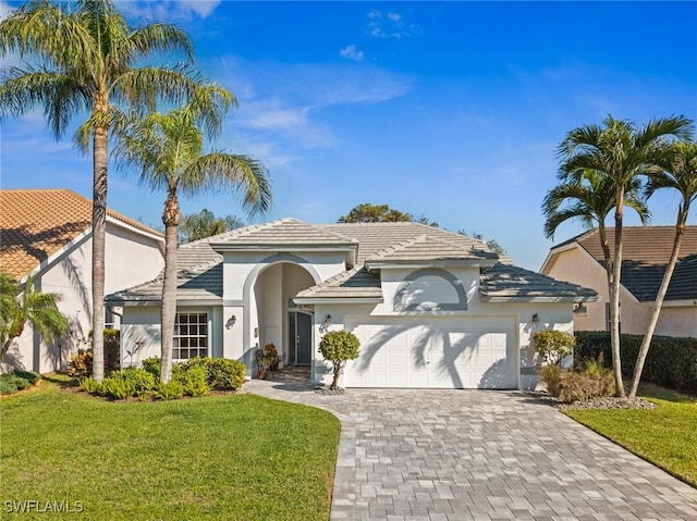 24973 Bay Cedar Dr, Bonita Springs, FL 34134 - mediterranean / spanish house featuring stucco siding, decorative driveway, a front yard, a garage, and a tiled roof