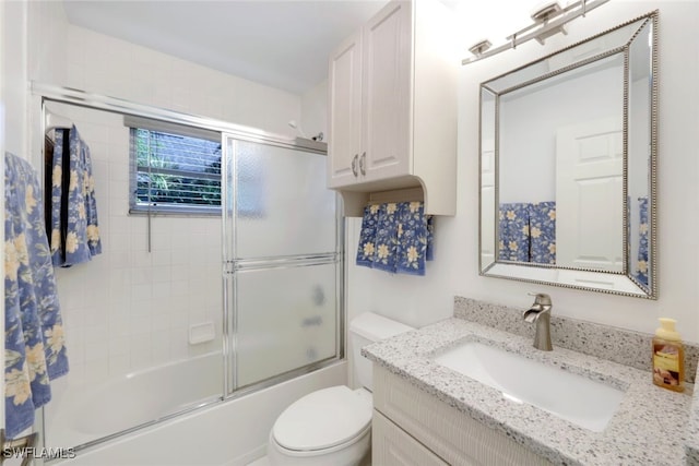 full bathroom featuring vanity, bath / shower combo with glass door, and toilet