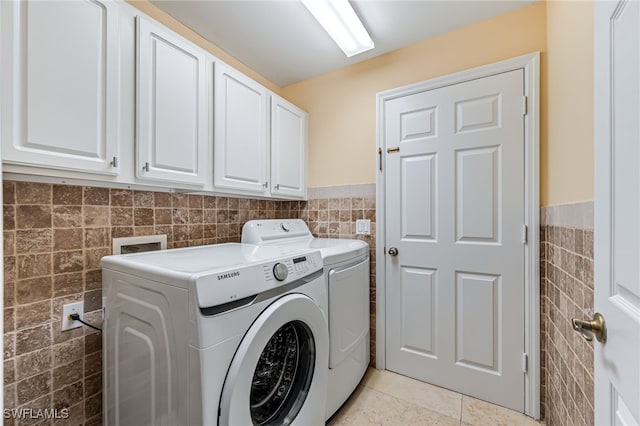 clothes washing area with cabinets, washer and dryer, tile walls, and light tile patterned floors