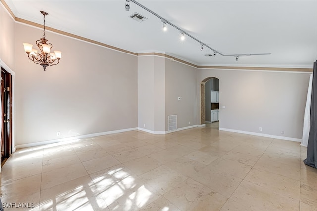 empty room featuring crown molding, track lighting, and a chandelier