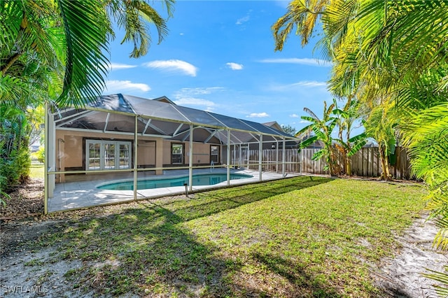 view of swimming pool with a lanai and a lawn