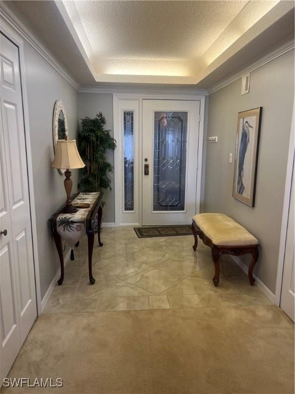 entrance foyer featuring light carpet, a textured ceiling, and a tray ceiling