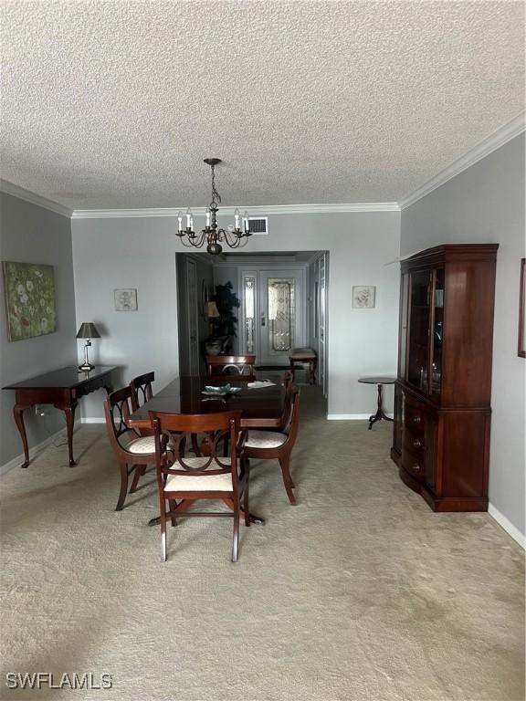 carpeted dining area with a textured ceiling, ornamental molding, and a chandelier