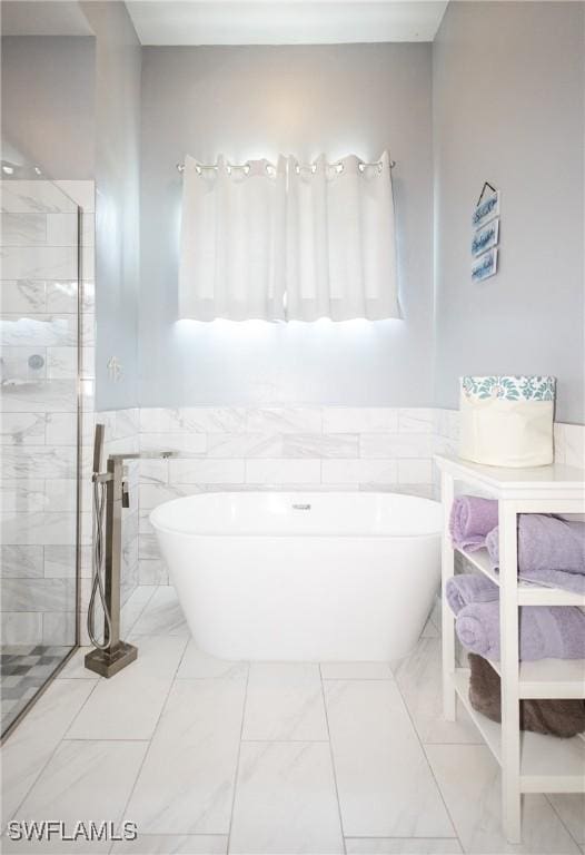 bathroom with shower with separate bathtub and tile walls