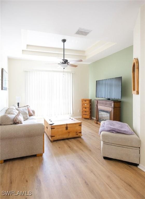 bedroom featuring light hardwood / wood-style floors, a raised ceiling, and ceiling fan