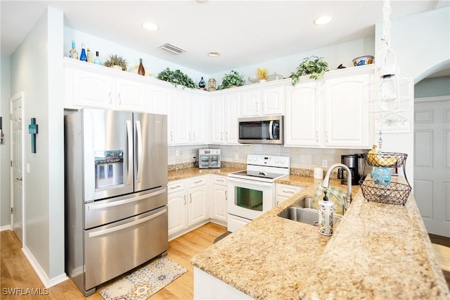 kitchen featuring sink, light stone counters, light hardwood / wood-style flooring, appliances with stainless steel finishes, and white cabinets